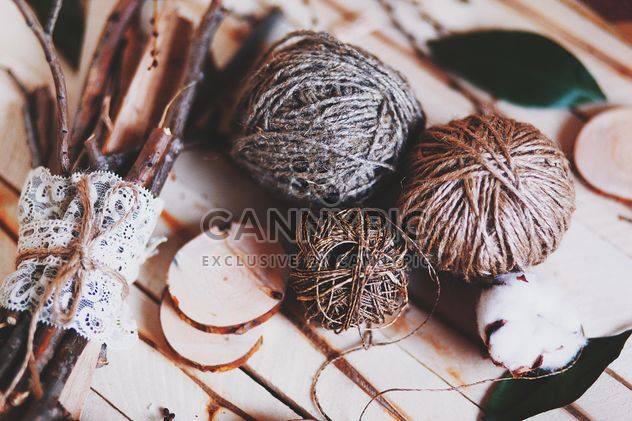 Skeins of wool, cotton and sticks on wooden background - image #136263 gratis