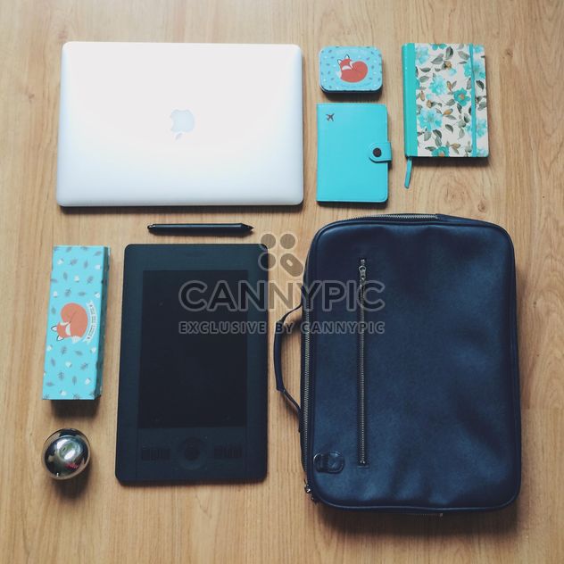 Macbook, wacom tablet, blue notebooks and black bag on wooden background - бесплатный image #271733