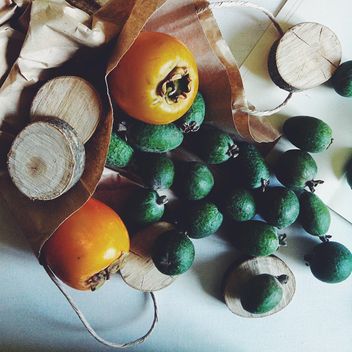 Feijoa and persimmons scattered from a paper package - image gratuit #272193 