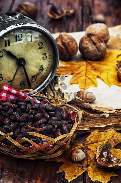 Walnuts, alarm clock and autumn leaves on the table - бесплатный image #302003