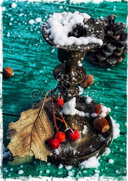 Candlestick, rowan berries, hazelnuts and dry leaf in snow on green wooden background - Free image #302033