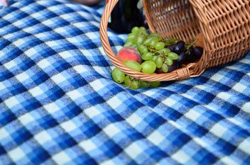 Fresh grapes and peach in basket on blue plaid - бесплатный image #346983
