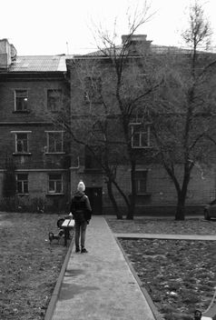 Person in front of house in town, black and white - бесплатный image #348033