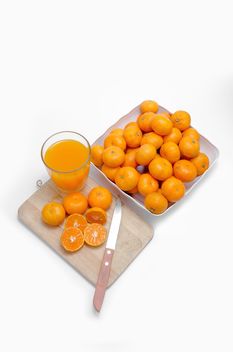 Oranges on the desk with knife and glass of juice on white background - бесплатный image #452523