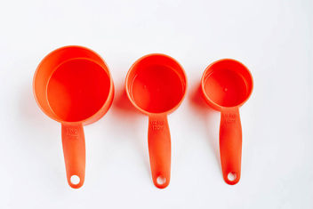 Top view of orange plastic measuring cups on white background. - image gratuit #452973 