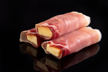 Rolled Pork Ham with yellow Cheddar cheese above black background - image gratuit #462573 