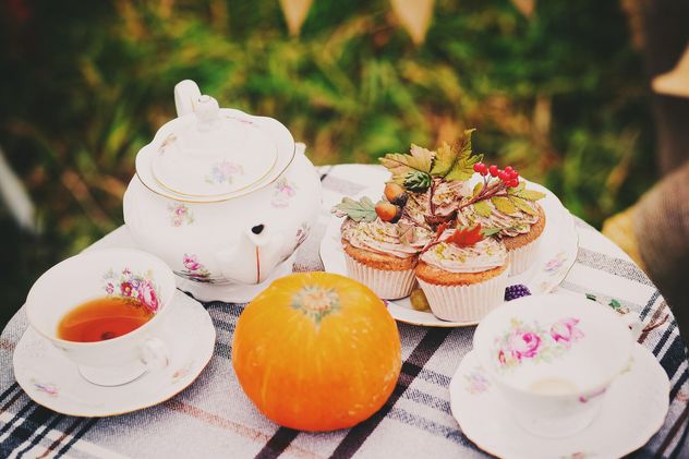 Tea in cups and teapot, cupcakes and pumpkin on the table - Free image #136203
