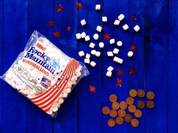 American marshmallows and coins on blue wooden background - image #183833 gratis