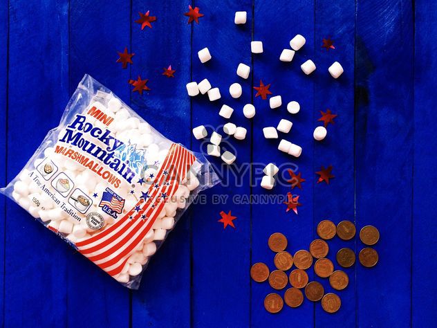 American marshmallows and coins on blue wooden background - бесплатный image #183833