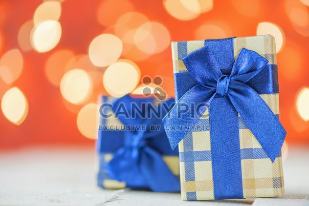 Small presents with blue ribbons on red blur background - бесплатный image #271603