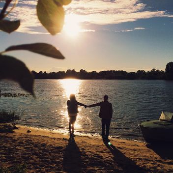 Girl and boy holding hands on the shore of the lake - image #271713 gratis
