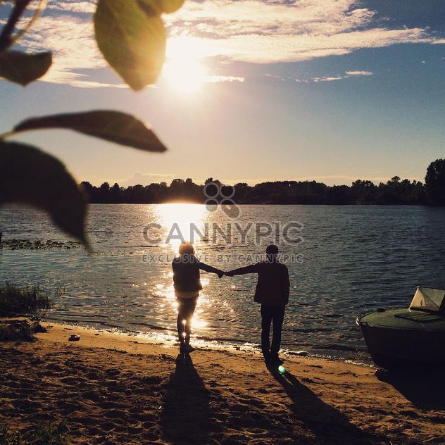 Girl and boy holding hands on the shore of the lake - image #271713 gratis