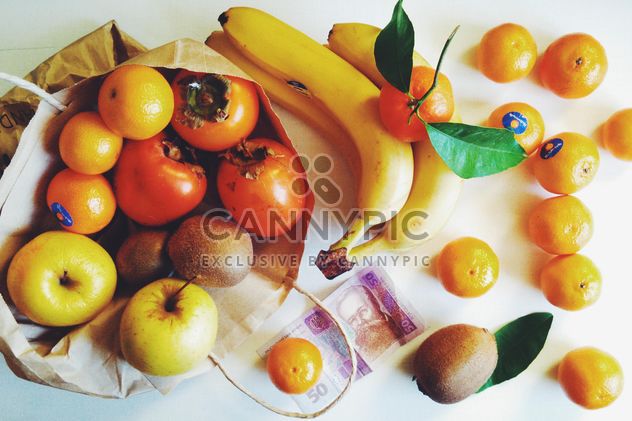 bananas, tangerines, kiwis, apples and persimmons in bag on white background - image #272273 gratis