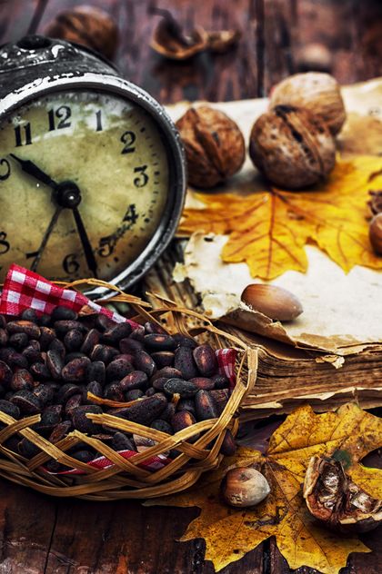 Walnuts, alarm clock and autumn leaves on the table - бесплатный image #302003