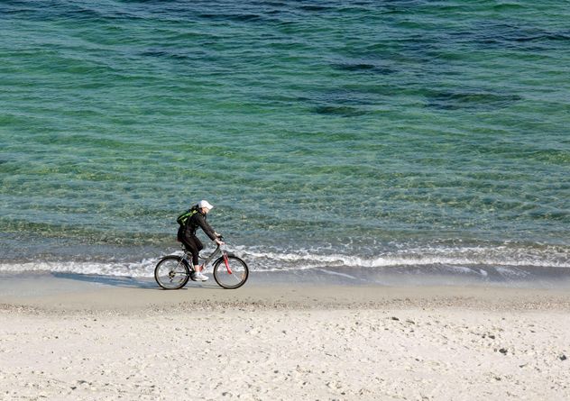 Woman riding a bicycle down the beach - Free image #330323