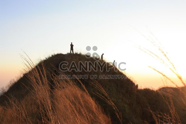 People on rock at sunset - image #338493 gratis