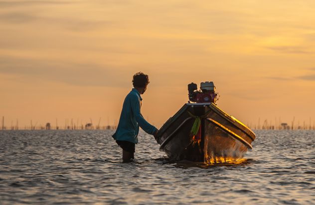 Fisherman with fishing boat at sunset - Free image #338573