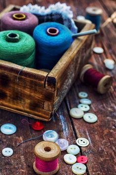 Colored buttons and sewing thread in wooden box on the table - image #342903 gratis