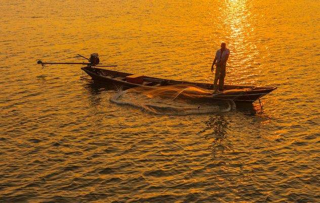 Fisherman in boat on sea at sunset - image #344623 gratis