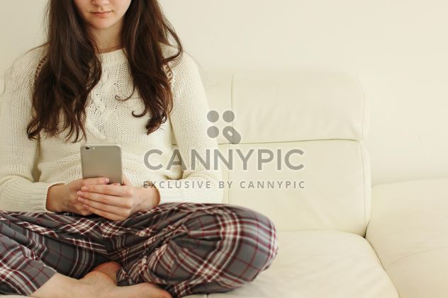 Girl with smartphone sitting on sofa - image #344633 gratis