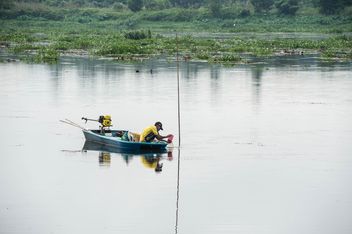 Fisherman in fishing boat on river - бесплатный image #347283