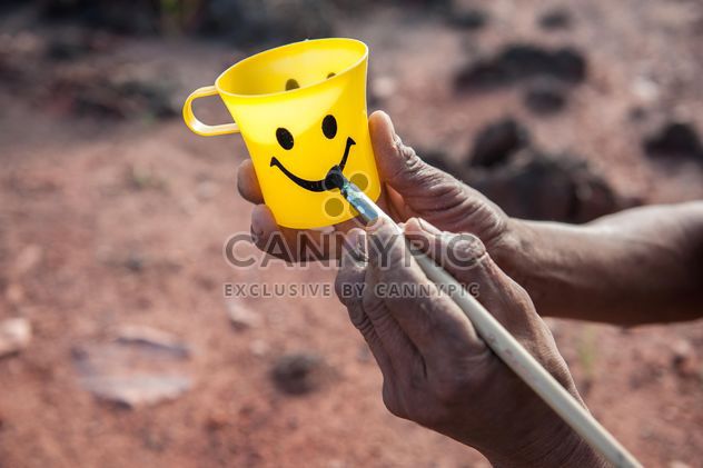 Hands painting smile on yellow cup - Free image #347313