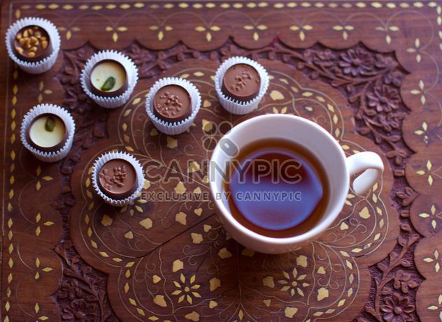 Cup of hot tea and candies on wooden background - бесплатный image #347913