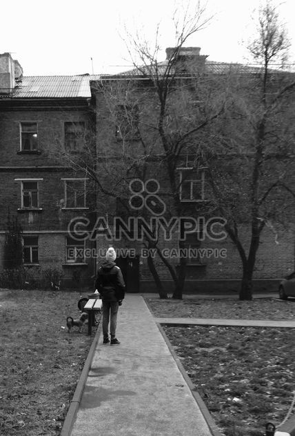 Person in front of house in town, black and white - бесплатный image #348033