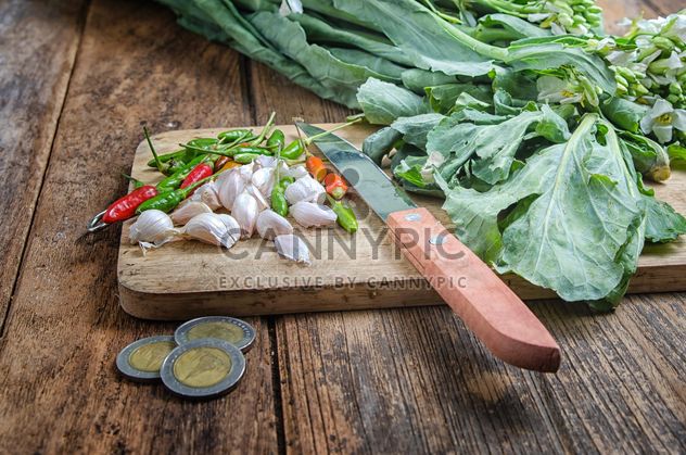 garlic and chili peppers on a wooden desk near coins on the table - Free image #452533