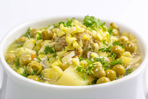 Close-up, soup with meatballs, peas and herbs in a white tureen - image #476933 gratis